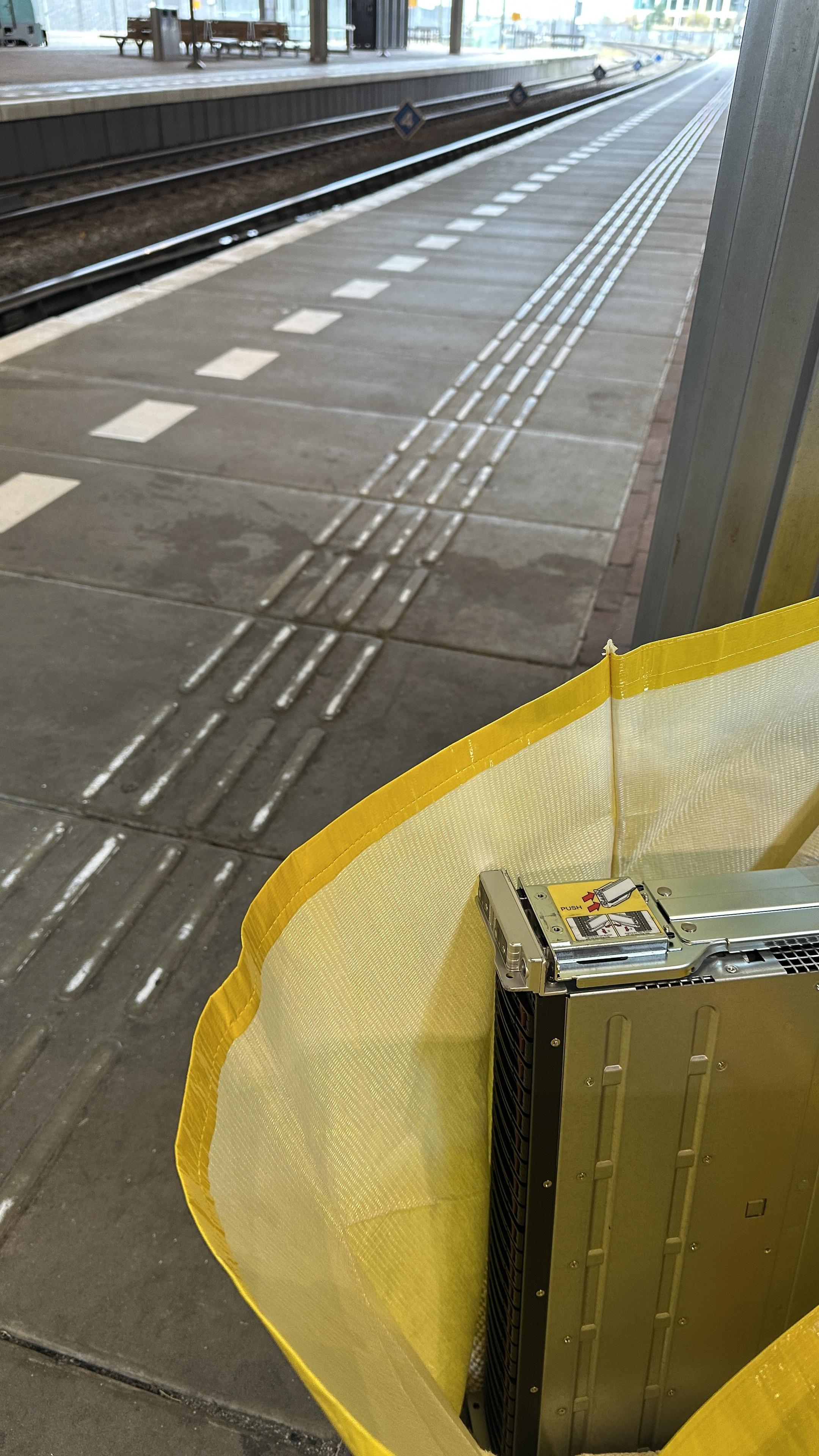 Server in a large yellow Lego bag sitting on a train station platform 